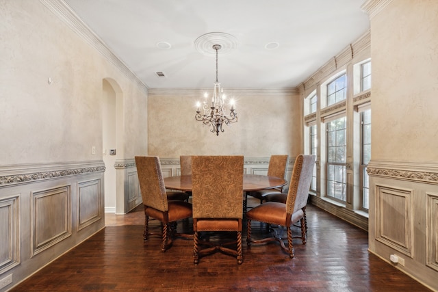 dining space with an inviting chandelier, crown molding, and dark wood-type flooring