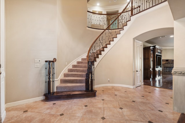 entryway with crown molding, a high ceiling, and light hardwood / wood-style floors