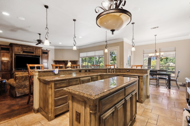 kitchen with crown molding, a center island, decorative light fixtures, and ceiling fan with notable chandelier