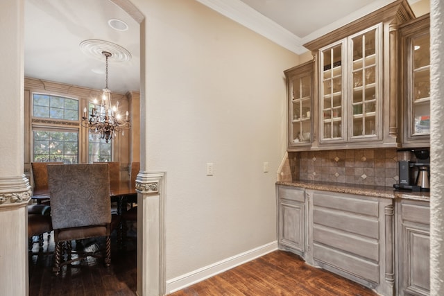 kitchen with tasteful backsplash, an inviting chandelier, light stone countertops, ornamental molding, and dark wood-type flooring