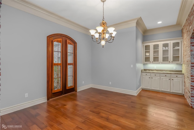 unfurnished dining area with french doors, ornamental molding, a chandelier, and light wood-type flooring