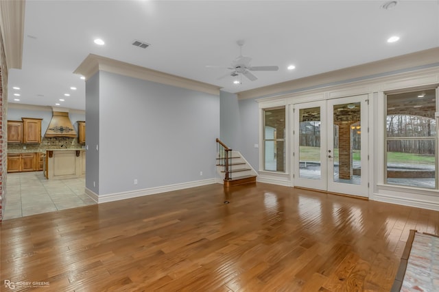 unfurnished living room featuring french doors, crown molding, ceiling fan, and light hardwood / wood-style flooring