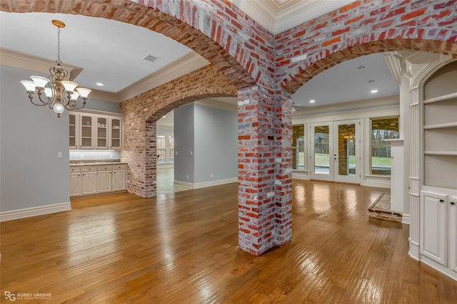 unfurnished living room with crown molding, light hardwood / wood-style floors, and brick wall