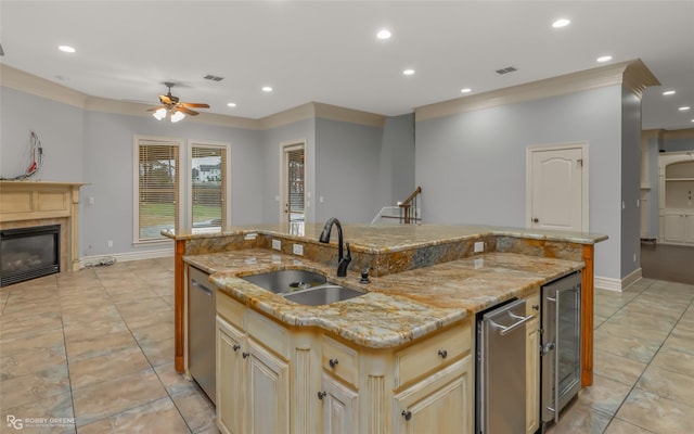 kitchen with light stone counters, sink, and an island with sink