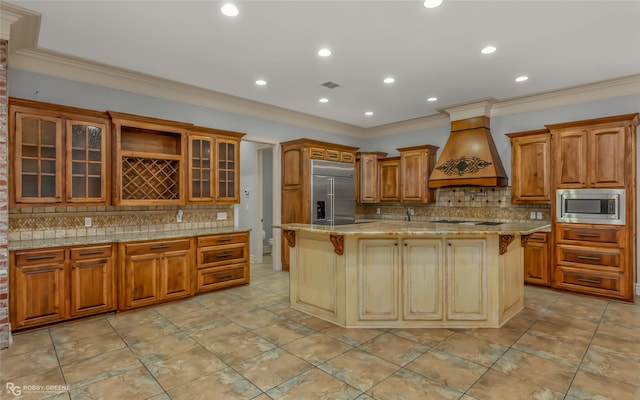 kitchen featuring a kitchen breakfast bar, a kitchen island with sink, built in appliances, light stone countertops, and custom range hood