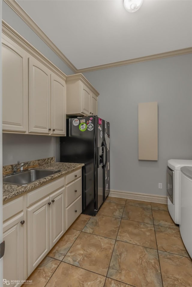 kitchen with sink, black fridge with ice dispenser, cream cabinets, and washer and dryer