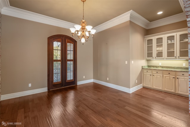 unfurnished dining area featuring ornamental molding, a notable chandelier, and wood-type flooring