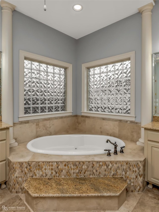 bathroom with a relaxing tiled tub, vanity, and ornate columns