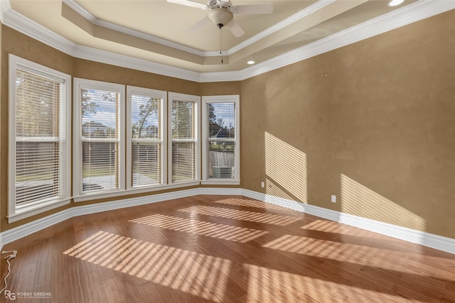 unfurnished room with ceiling fan, a tray ceiling, wood-type flooring, and ornamental molding