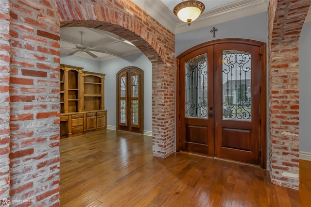 entrance foyer featuring hardwood / wood-style flooring, crown molding, brick wall, and french doors