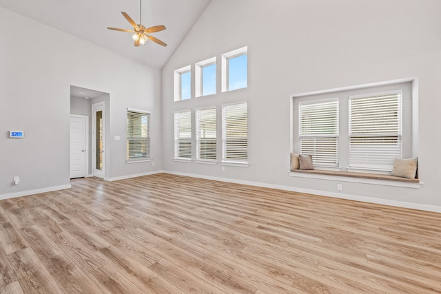 unfurnished living room featuring a wealth of natural light, high vaulted ceiling, and light hardwood / wood-style floors