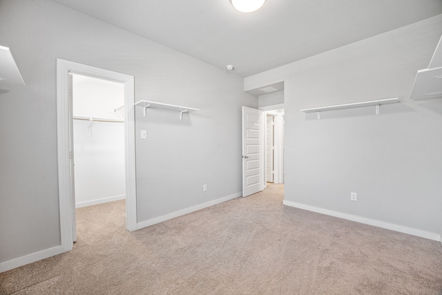 unfurnished bedroom with a spacious closet, light carpet, and a closet