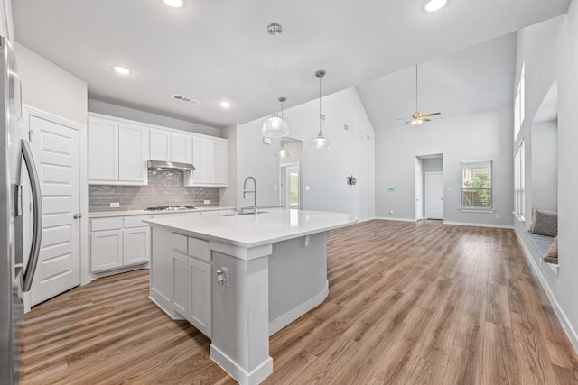 kitchen with white cabinets, ceiling fan, light wood-type flooring, an island with sink, and gas cooktop