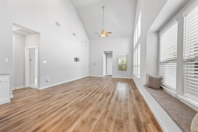 unfurnished living room with ceiling fan, light hardwood / wood-style flooring, high vaulted ceiling, and a healthy amount of sunlight