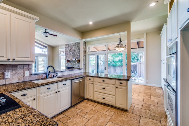 kitchen featuring kitchen peninsula, backsplash, dark stone counters, sink, and stainless steel appliances