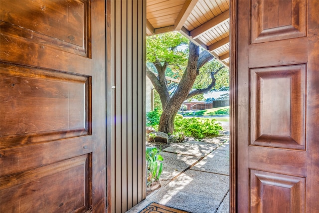 doorway to outside featuring wood walls, lofted ceiling with beams, and wooden ceiling