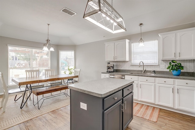 kitchen with a center island, hanging light fixtures, white cabinetry, decorative backsplash, and light hardwood / wood-style flooring