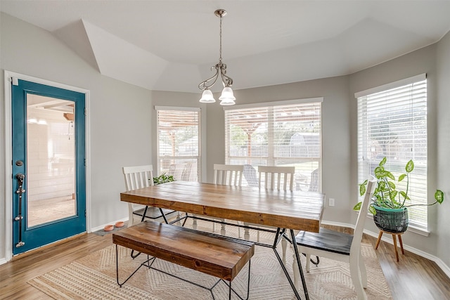 dining area featuring a chandelier, vaulted ceiling, and hardwood / wood-style flooring