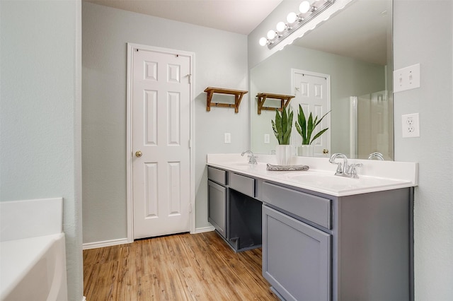 bathroom with vanity, hardwood / wood-style floors, and a tub to relax in