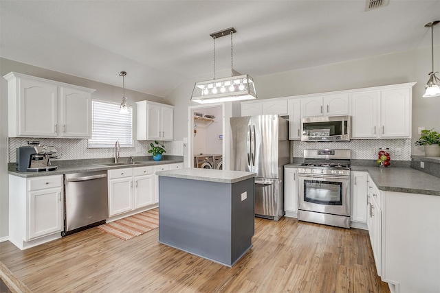 kitchen featuring pendant lighting, washing machine and clothes dryer, stainless steel appliances, and white cabinets