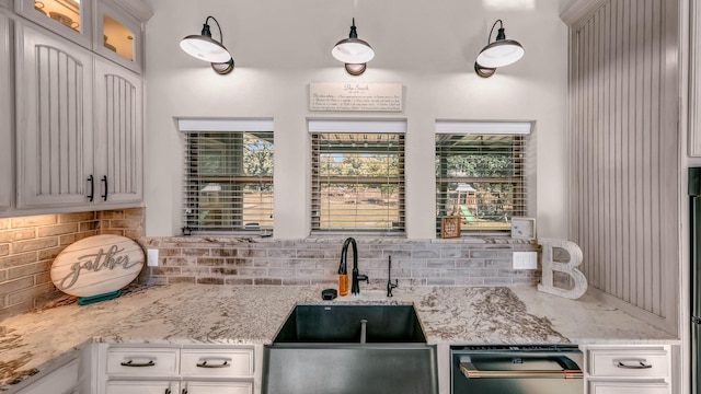 kitchen featuring white cabinets, decorative backsplash, sink, and light stone counters