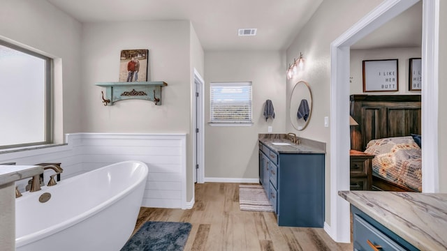 bathroom featuring vanity, hardwood / wood-style floors, and a bath