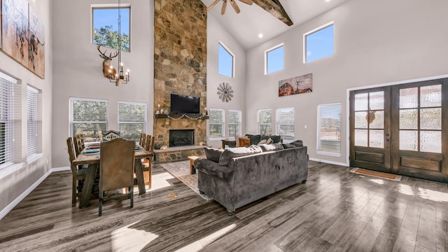 living room with a stone fireplace, dark hardwood / wood-style floors, a towering ceiling, french doors, and beam ceiling