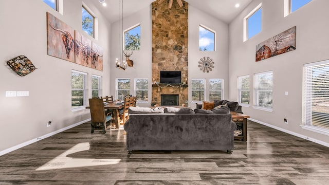 living room with a stone fireplace, a wealth of natural light, and a high ceiling