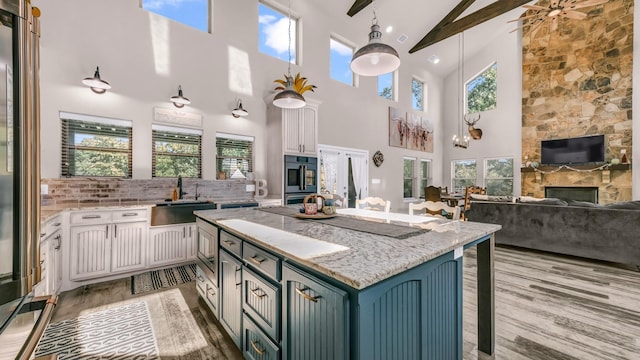 kitchen featuring high vaulted ceiling, sink, white cabinetry, and a fireplace