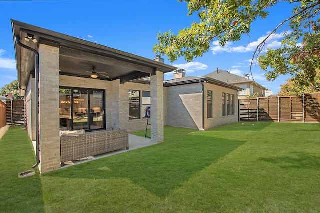 rear view of house featuring a lawn and ceiling fan