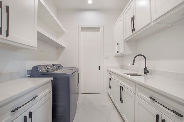 clothes washing area featuring cabinets, washer and dryer, and sink