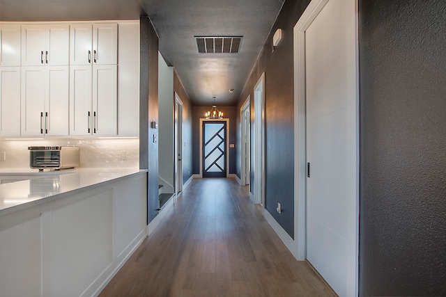 corridor featuring a notable chandelier and hardwood / wood-style floors