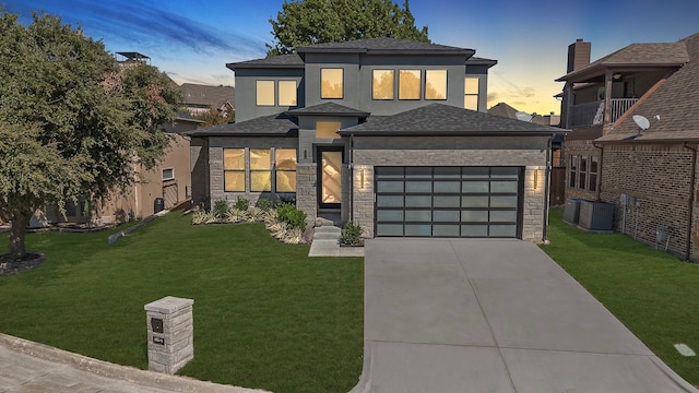 view of front facade with central air condition unit, a lawn, and a garage