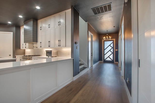 kitchen with white cabinetry, a notable chandelier, decorative light fixtures, and dark hardwood / wood-style floors