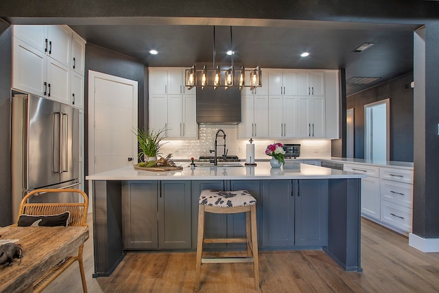 kitchen featuring white cabinetry, light hardwood / wood-style floors, pendant lighting, and high end fridge