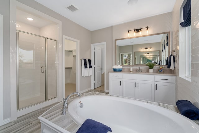 bathroom featuring vanity, independent shower and bath, and wood-type flooring