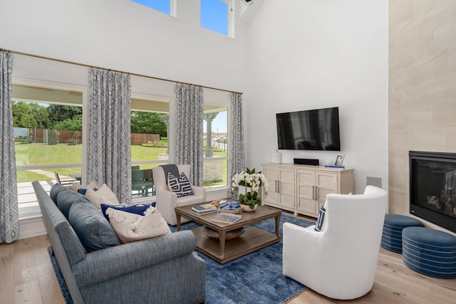 living room featuring a high ceiling, a tile fireplace, and light wood-type flooring