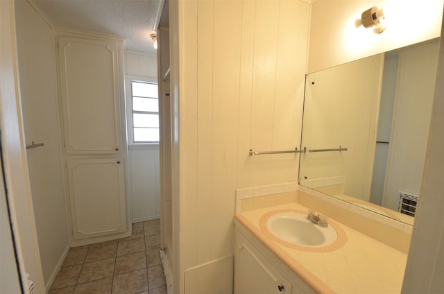 bathroom with vanity, wooden walls, a textured ceiling, and tile patterned flooring