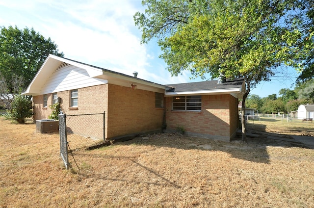 view of side of home featuring cooling unit and a yard