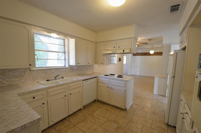 kitchen with kitchen peninsula, decorative backsplash, a textured ceiling, sink, and white appliances