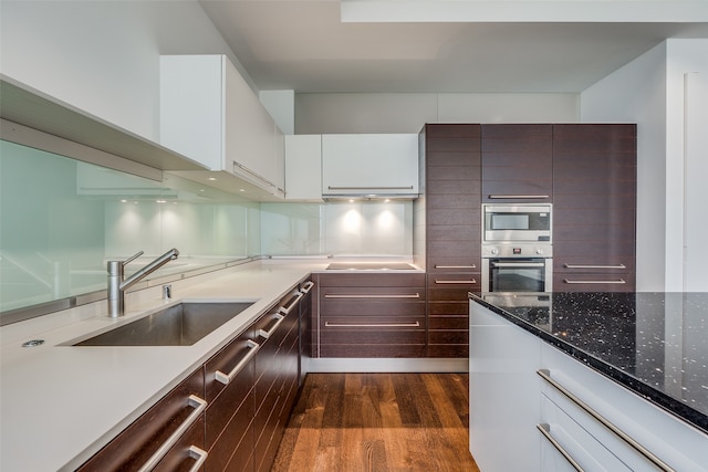 kitchen featuring stone counters, dishwasher, sink, white cabinets, and dark wood-type flooring