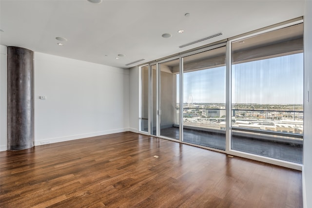 unfurnished room featuring hardwood / wood-style flooring and a wall of windows