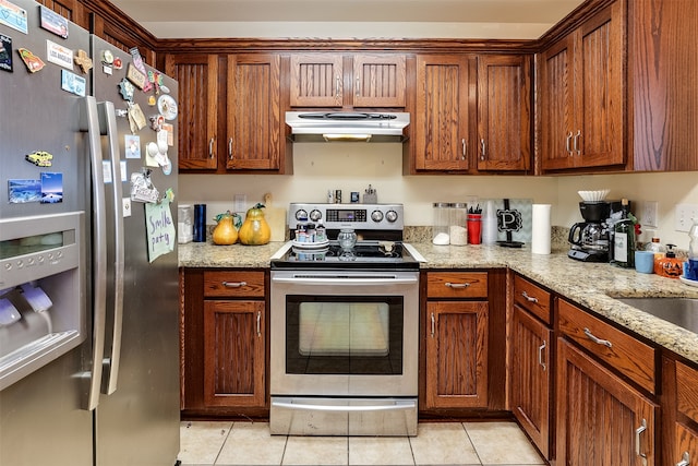 kitchen with stainless steel appliances, light tile patterned floors, and light stone counters