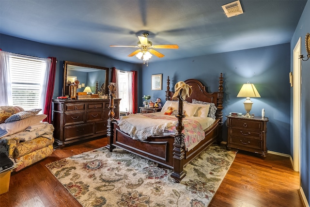 bedroom featuring dark hardwood / wood-style floors, ceiling fan, and multiple windows