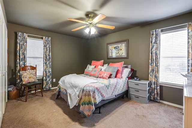 bedroom with ceiling fan, multiple windows, and light carpet