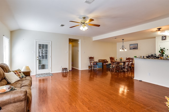 living room with ceiling fan with notable chandelier and dark hardwood / wood-style flooring