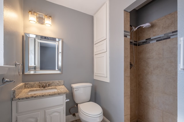 bathroom with vanity, toilet, and a tile shower