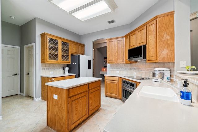 kitchen featuring sink, a center island, light tile patterned floors, appliances with stainless steel finishes, and tasteful backsplash