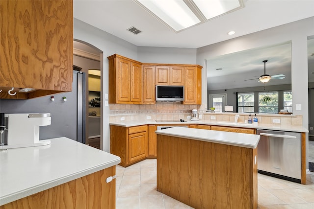 kitchen with kitchen peninsula, backsplash, a kitchen island, dishwasher, and sink