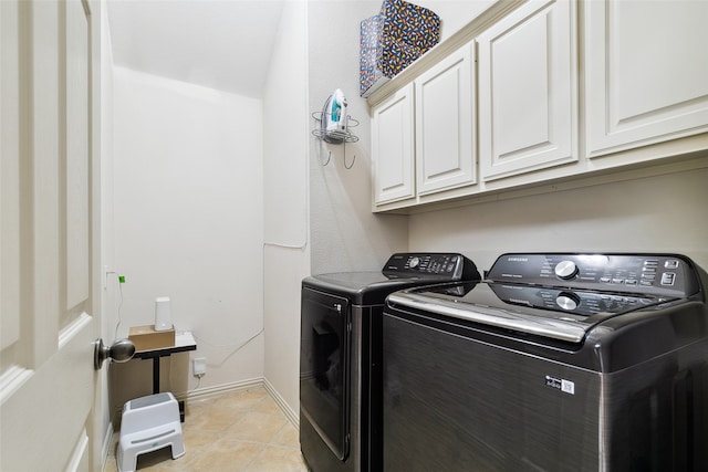 laundry area with washing machine and dryer, light tile patterned floors, and cabinets